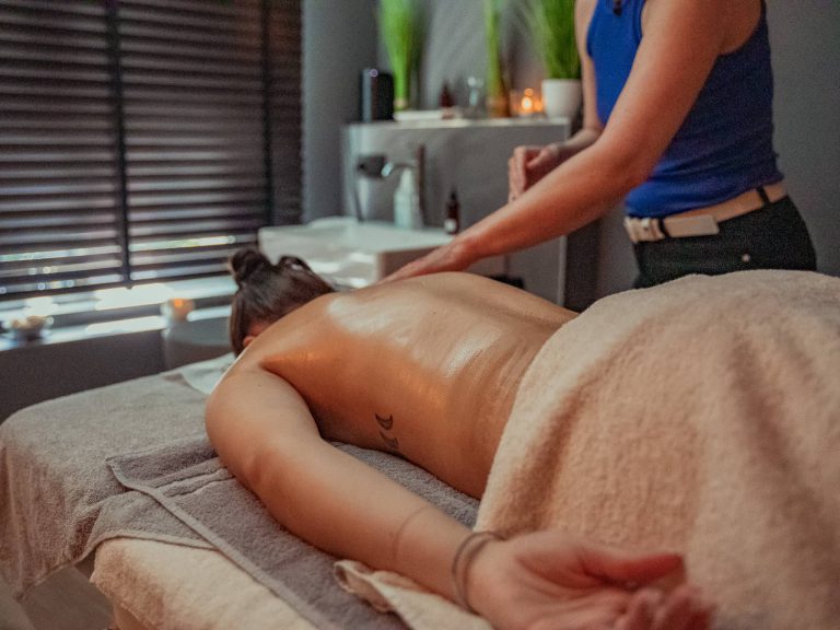 Eine frau liegt auf einer Massageliege mit dem Gesicht nach unten und wird massiert.